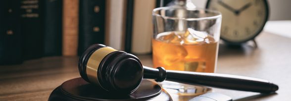 DUI concept. Law gavel, alcohol and car keys on a wooden desk, dark background