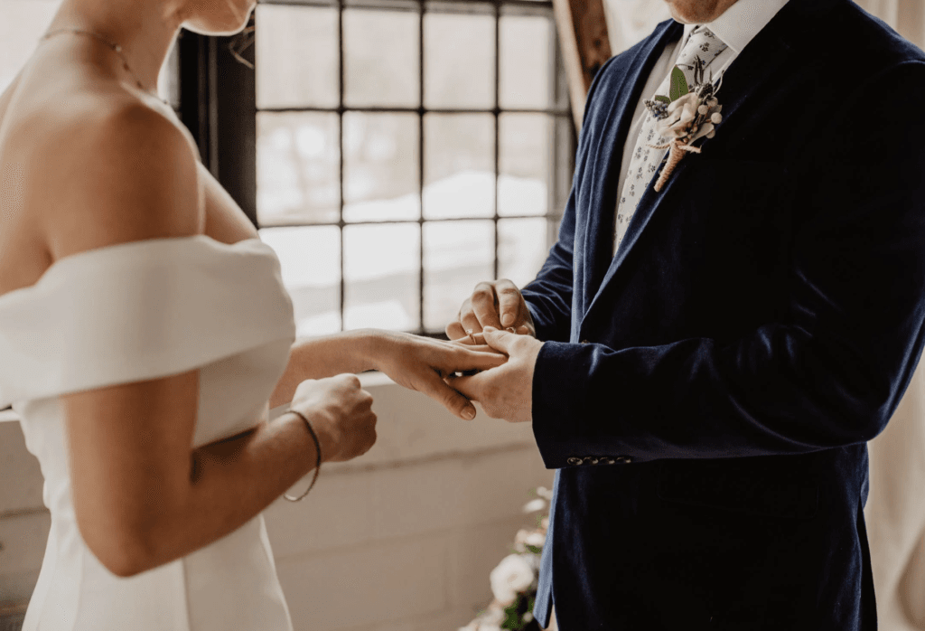 groom putting ring on bride's finger