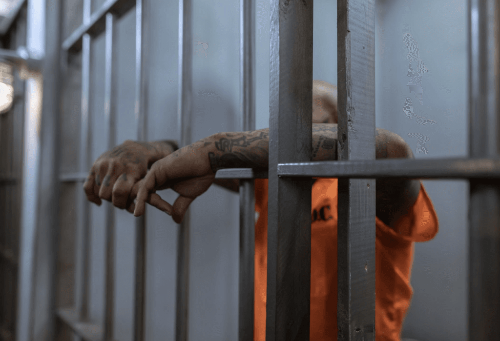 man with tattoos in jail cell