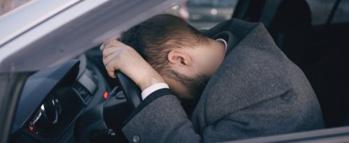 A man putting his head against his steering wheel in depair