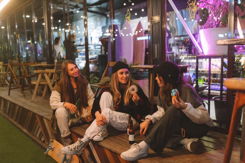 three women sitting outside club drinking