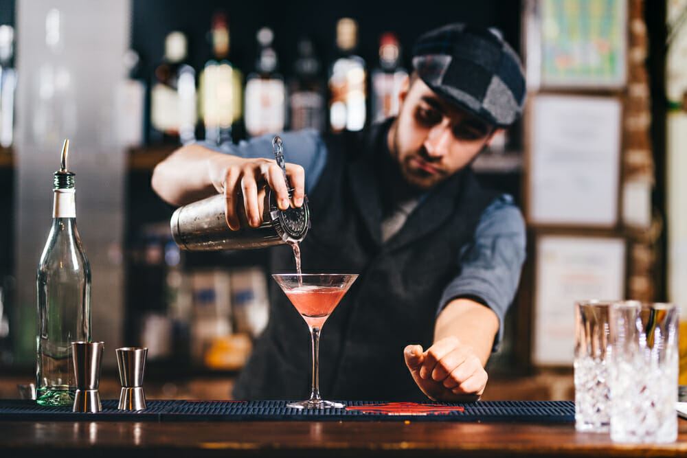 Portrait of vintage barman workin in bar. Pouring and preparing cocktails