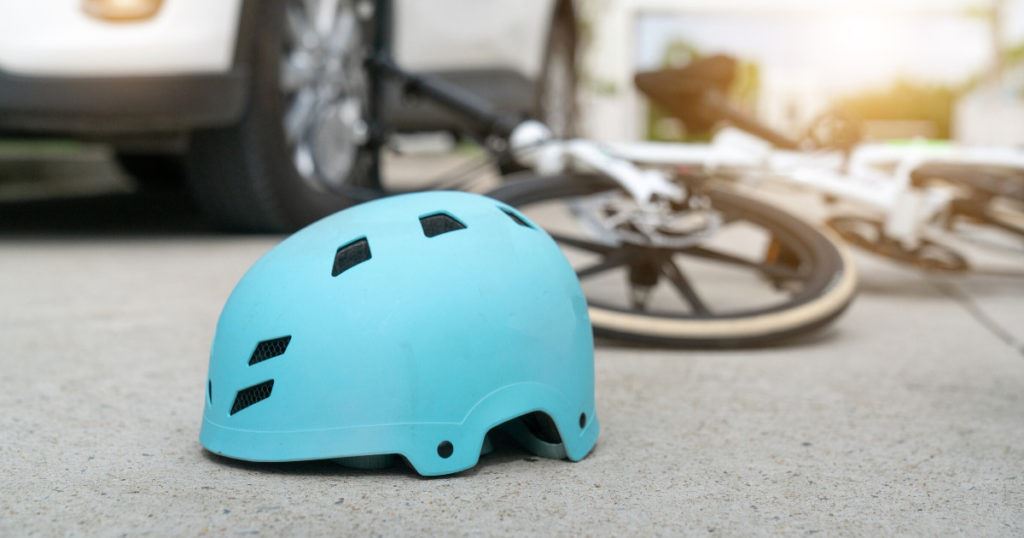 Blue helmet and bike on ground in front of car