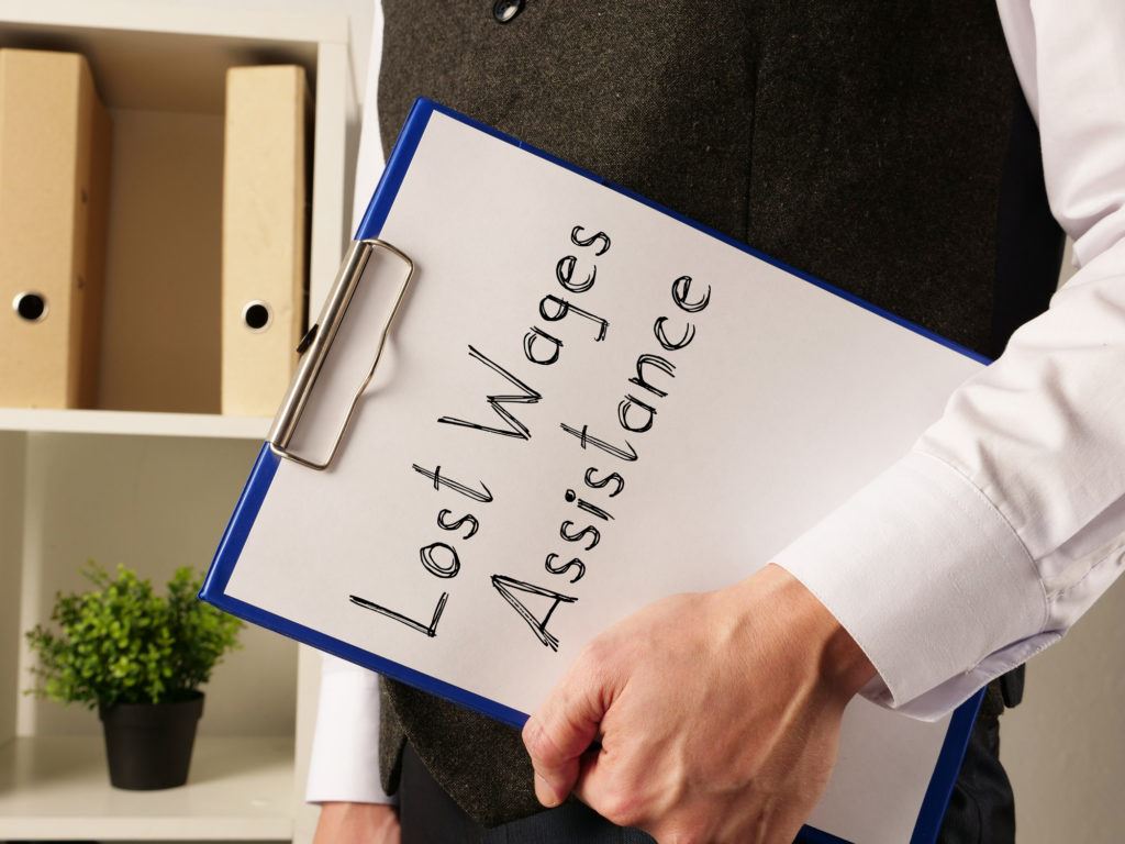 A photograph of a person holding a clipboard with 'lost wages assistance' written on it.