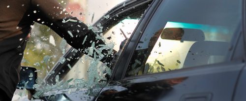 man breaking car window