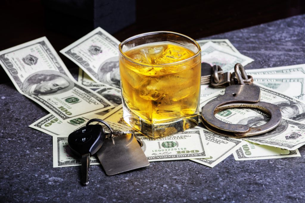 glass of whiskey sitting on pile of cash